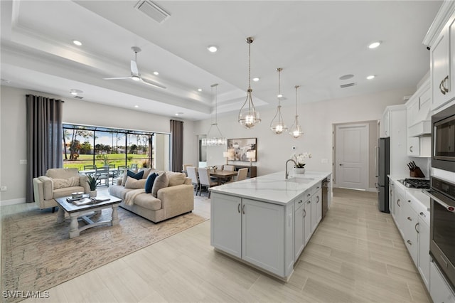 kitchen featuring visible vents, a kitchen island with sink, stainless steel appliances, a raised ceiling, and open floor plan