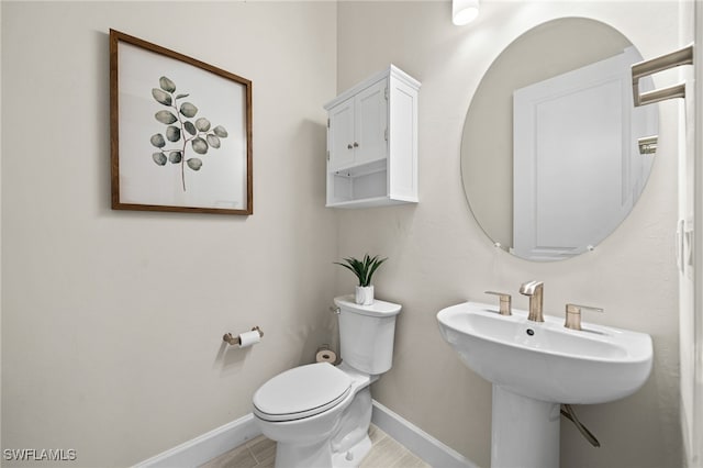 half bathroom with a sink, baseboards, and toilet