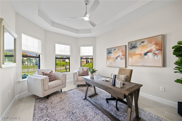 home office with baseboards, a raised ceiling, and ceiling fan