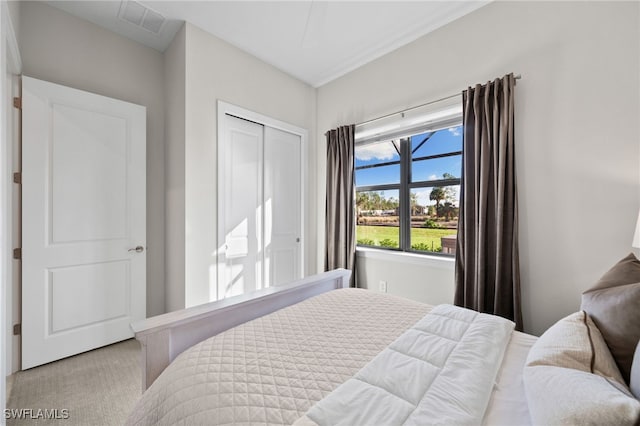 bedroom with visible vents, light carpet, and a closet