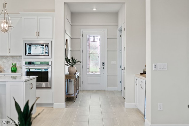 foyer entrance with light tile patterned floors and baseboards
