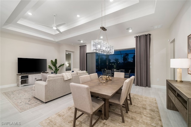 dining room featuring a tray ceiling, baseboards, ornamental molding, and ceiling fan with notable chandelier