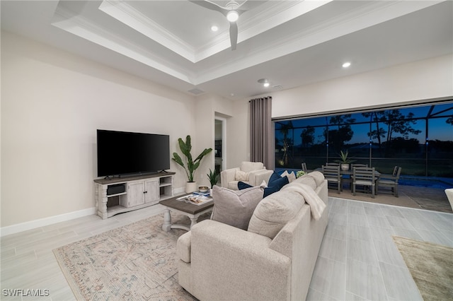 living room with crown molding, baseboards, recessed lighting, a raised ceiling, and a ceiling fan