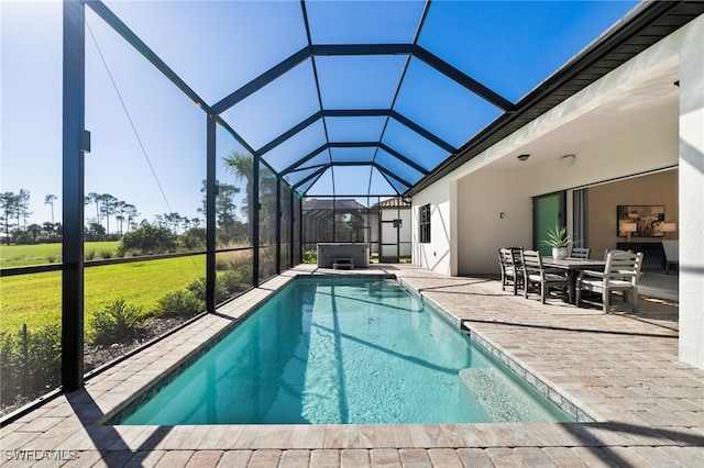 outdoor pool featuring glass enclosure, a patio, a yard, and a hot tub