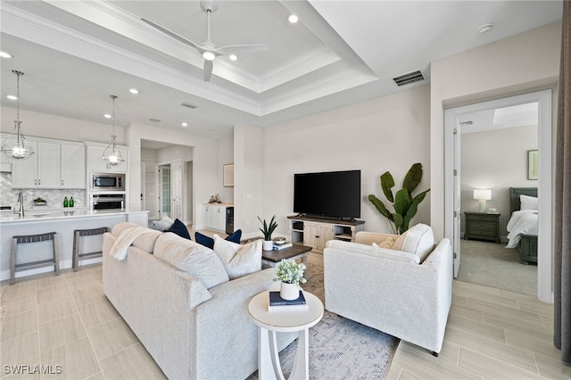 living room with visible vents, crown molding, ceiling fan, a tray ceiling, and recessed lighting