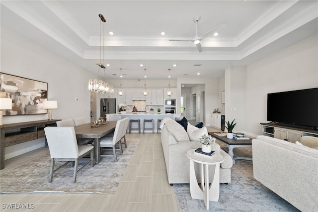 living room with recessed lighting, a tray ceiling, ceiling fan, and ornamental molding