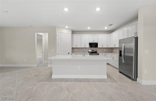 3056 Weston Manor Dr, Alva, FL 33920 - kitchen with tasteful backsplash, a center island with sink, light countertops, appliances with stainless steel finishes, and white cabinetry