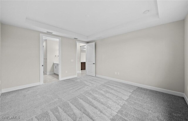 3056 Weston Manor Dr, Alva, FL 33920 - unfurnished bedroom featuring a raised ceiling, baseboards, ensuite bathroom, and light carpet