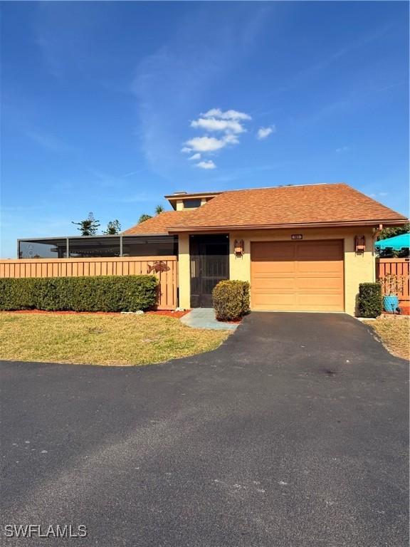 6411 Royal Woods Dr, Fort Myers, FL 33908 - view of front of home featuring a shingled roof, a fenced front yard, stucco siding, a garage, and driveway