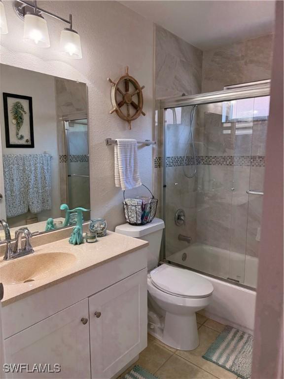 6411 Royal Woods Dr, Fort Myers, FL 33908 - bathroom featuring tile patterned flooring, toilet, vanity, and enclosed tub / shower combo