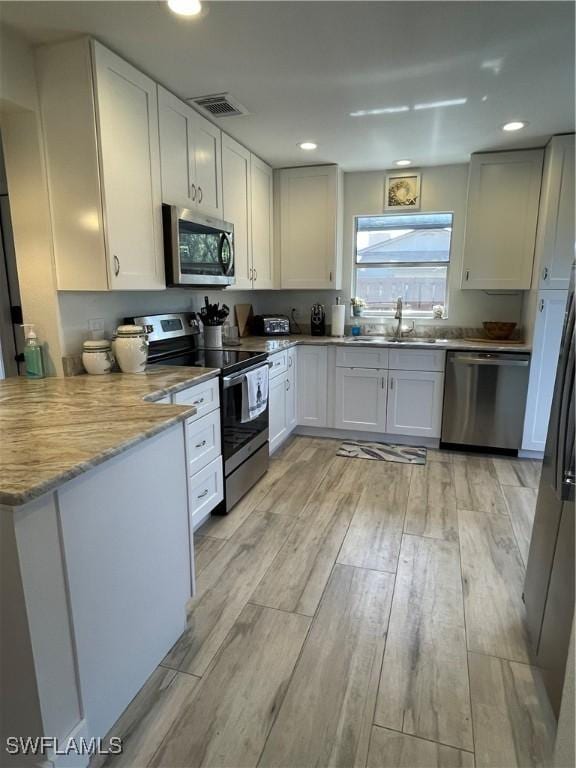 6411 Royal Woods Dr, Fort Myers, FL 33908 - kitchen featuring visible vents, a sink, stainless steel appliances, white cabinets, and light wood-type flooring
