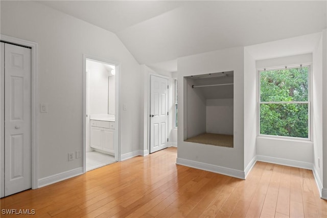 20732 Charing Cross Cir, Estero, FL 33928 - unfurnished bedroom featuring light wood-style flooring, baseboards, ensuite bathroom, and lofted ceiling