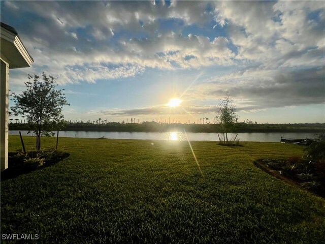 view of green lawn featuring a water view