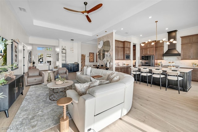 living area featuring ceiling fan, light wood finished floors, a raised ceiling, a chandelier, and recessed lighting