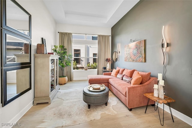living room featuring a tray ceiling, wood finished floors, and baseboards