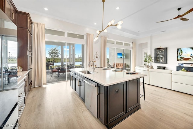 kitchen with a sink, stainless steel dishwasher, light wood finished floors, open floor plan, and recessed lighting