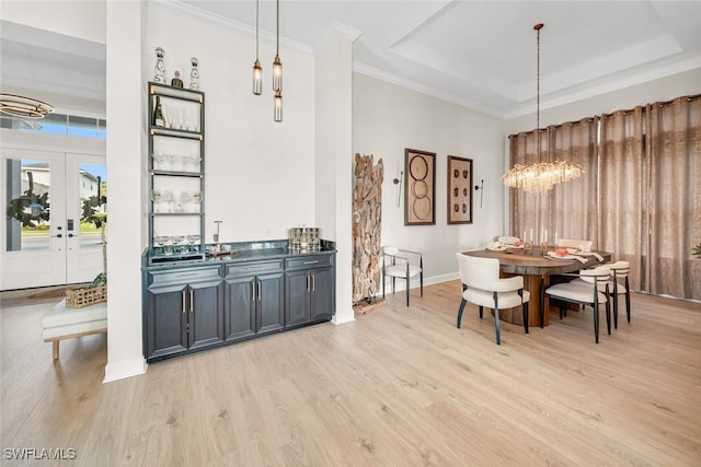dining room featuring a raised ceiling, light wood-type flooring, a chandelier, crown molding, and baseboards