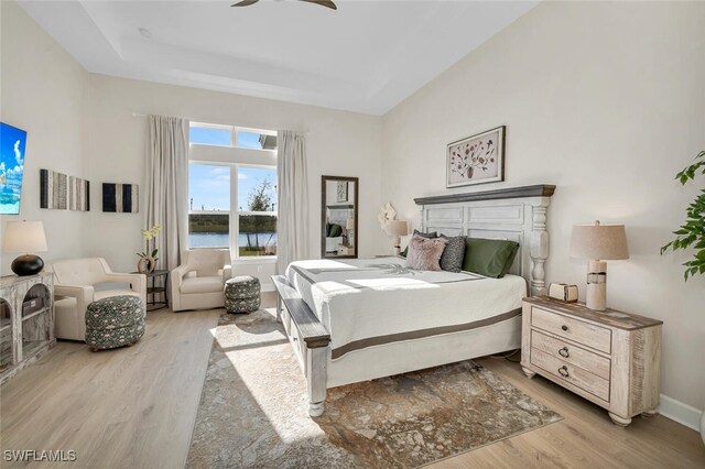 15445 Turin Dr, Naples, FL 34114 - bedroom featuring wood finished floors, a raised ceiling, ceiling fan, a water view, and baseboards