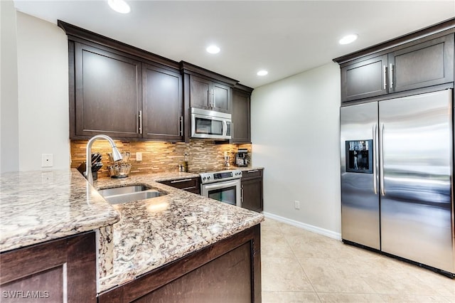 8201 Grand Palm Dr Unit 4, Estero, FL 33967 - kitchen featuring stainless steel appliances, a sink, light stone countertops, decorative backsplash, and dark brown cabinetry
