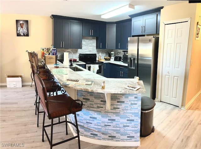 4844 Golfview Blvd, Lehigh Acres, FL 33973 - kitchen featuring a breakfast bar area, a peninsula, range with electric cooktop, decorative backsplash, and stainless steel refrigerator with ice dispenser