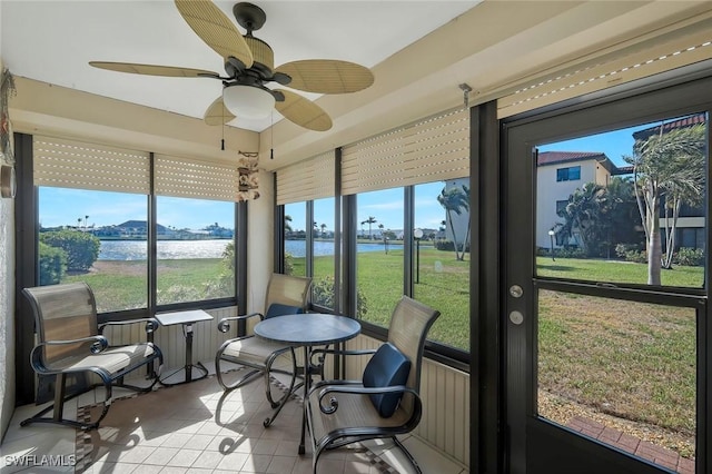 sunroom / solarium featuring a water view, tile patterned floors, and a ceiling fan