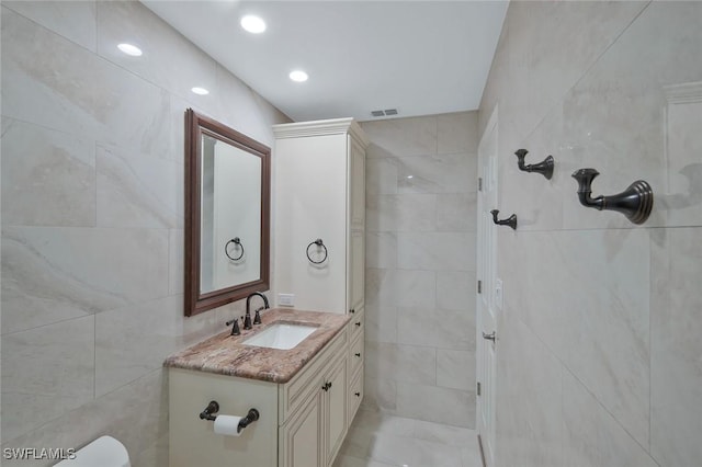 bathroom featuring vanity, toilet, tile walls, and visible vents