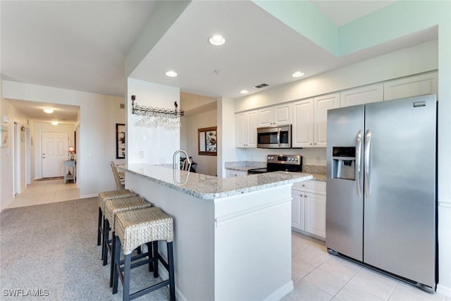 16605 Lake Circle Dr Unit 337, Fort Myers, FL 33908 - kitchen featuring a breakfast bar area, light stone counters, light tile patterned flooring, stainless steel appliances, and white cabinetry