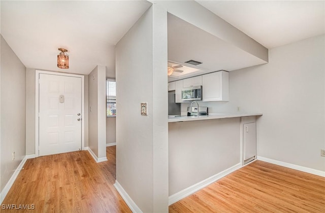 entryway featuring light wood finished floors, visible vents, ceiling fan, and baseboards
