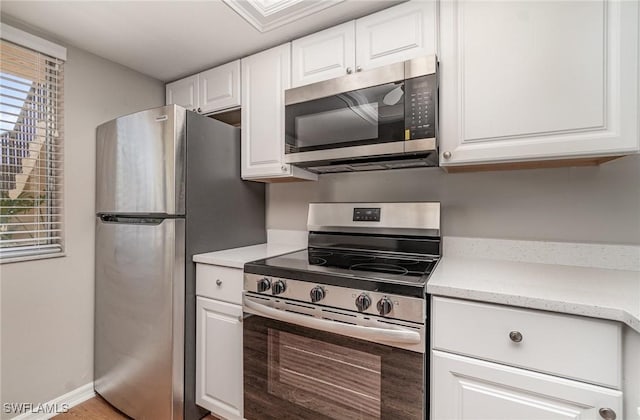 kitchen featuring stainless steel appliances, baseboards, and white cabinetry