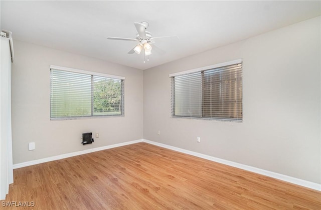 spare room with light wood finished floors, a ceiling fan, and baseboards