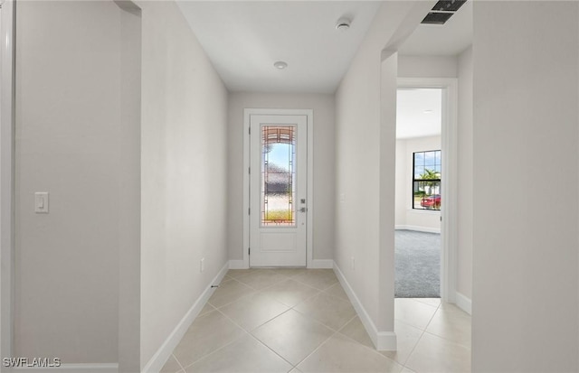 doorway with baseboards, light tile patterned flooring, and visible vents