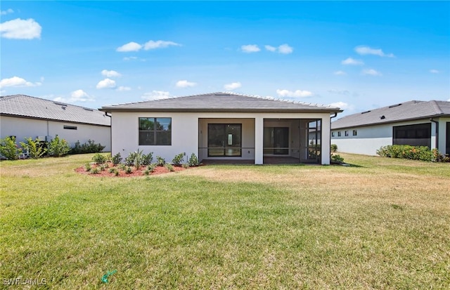back of house featuring a sunroom, stucco siding, and a yard