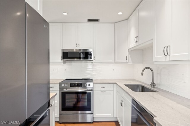 13 Knights Bridge Rd Unit A49, Naples, FL 34112 - kitchen with appliances with stainless steel finishes, a sink, light stone counters, white cabinetry, and backsplash