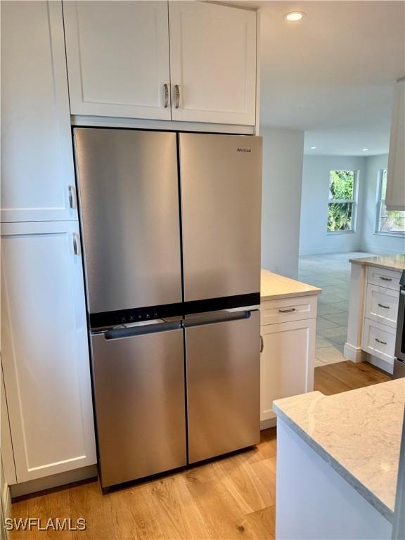 13 Knights Bridge Rd Unit A49, Naples, FL 34112 - kitchen with freestanding refrigerator, light wood-style floors, white cabinetry, recessed lighting, and light stone countertops