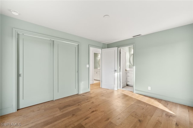 13 Knights Bridge Rd Unit A49, Naples, FL 34112 - unfurnished bedroom with light wood-style flooring, a closet, baseboards, and ensuite bathroom