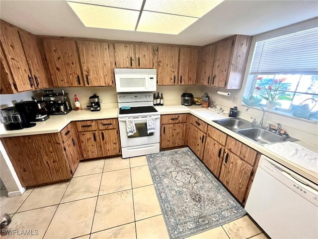 kitchen with white appliances, light tile patterned floors, a sink, light countertops, and brown cabinets