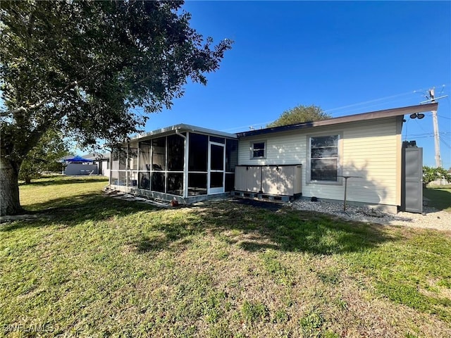 back of property with a yard and a sunroom