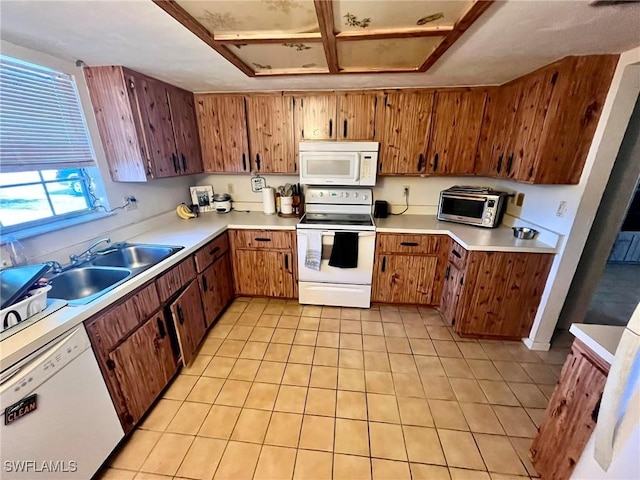 kitchen with brown cabinets, white appliances, light countertops, and a sink