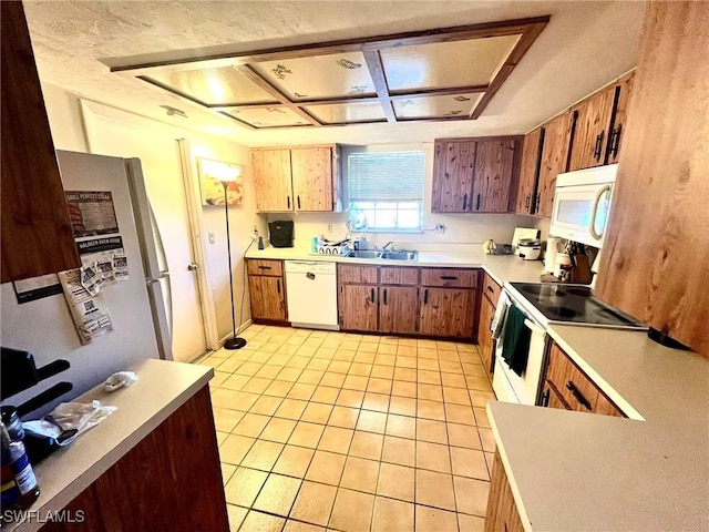 kitchen with white appliances, light tile patterned floors, light countertops, and a sink