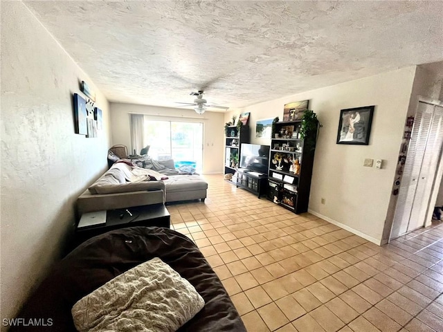 living area featuring a ceiling fan, baseboards, tile patterned flooring, a textured ceiling, and a textured wall