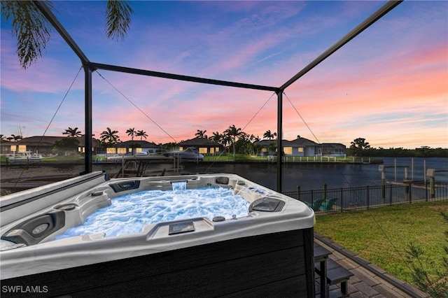 view of patio / terrace featuring a lanai, washer / clothes dryer, fence, and a hot tub
