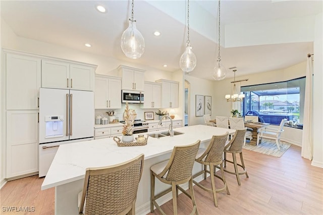 kitchen featuring a center island with sink, a breakfast bar area, light wood-style floors, stainless steel appliances, and a sink