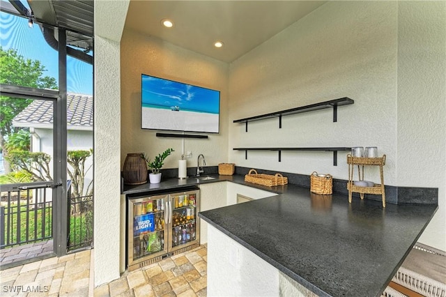 view of patio with a sink, an outdoor kitchen, and a lanai