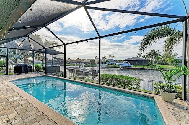 pool featuring glass enclosure, a grill, a patio, and a water view