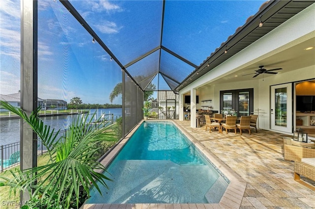 outdoor pool featuring a water view, a lanai, outdoor dining area, a patio area, and a ceiling fan