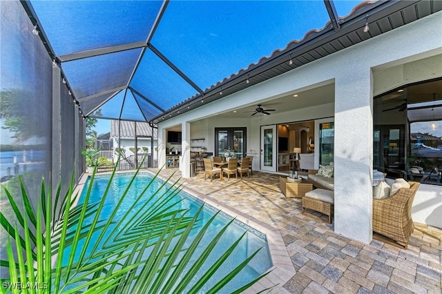 view of pool featuring a lanai, french doors, outdoor lounge area, a patio, and a ceiling fan