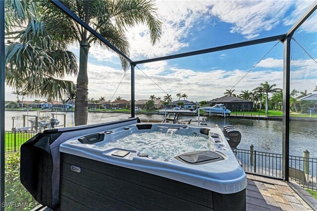 exterior space with a lanai, a water view, and a hot tub