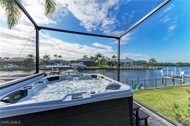 view of patio featuring glass enclosure, a water view, and fence