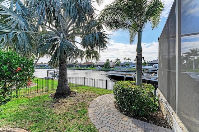 view of yard featuring a dock, a water view, and fence