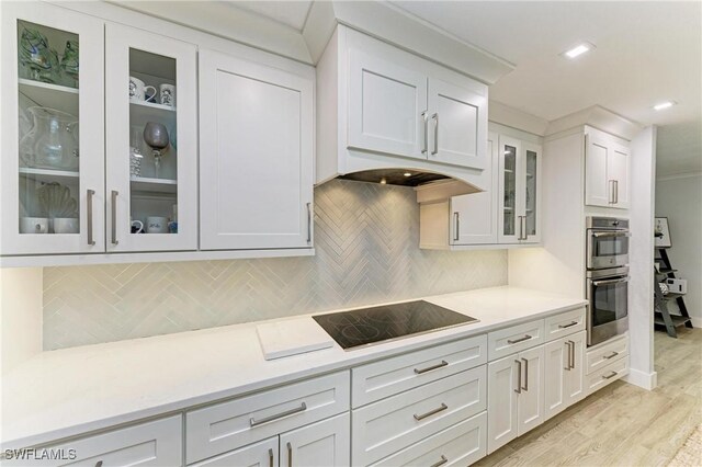 621 Trabue Ave, Punta Gorda, FL 33950 - kitchen featuring black electric cooktop, light countertops, glass insert cabinets, double oven, and light wood-type flooring